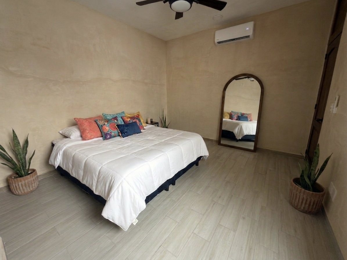 Primary bedroom with king bed and arched floor mirror